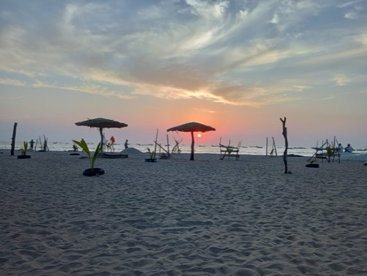 Sunset over the Atlantic from the beach, the sun dropping behind the thatched parasols.